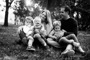 foto familiar de pareja con tres niños sentados en el campo