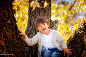 niño riéndose sentado en un árbol