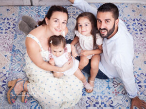 foto de familia con madre, padre y dos niñas sentados en un suelo de mosaico