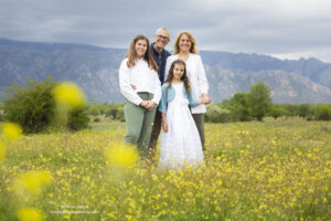 retrato de familia con niña vestida de primera comunión entre las flores y la Cuerda Larga de fondo