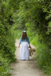 niña vestida de primera comunión de espaldas caminando en el campo