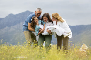 familia cogiendo en brazos a su hija vestida de primera comunión entre las flores
